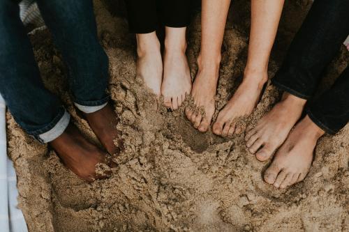 Friends soaking their feet in the sand - 1079787