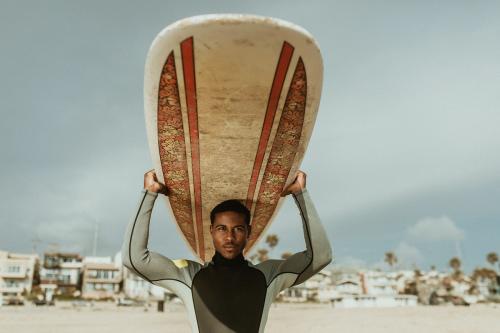 Surfer carrying a surfboard at the beach - 1079799