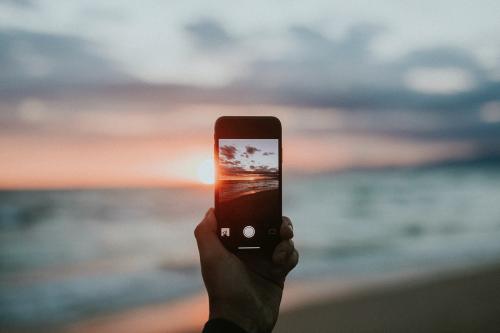 Man taking a picture of the sunset on the beach - 1079816