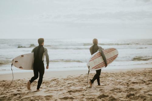 Surfers running on the beach - 1079934