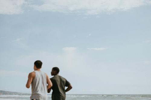 Friends jogging at the beach together - 1079936