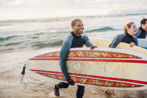 Cheerful friends surfing at the beach - 1079973