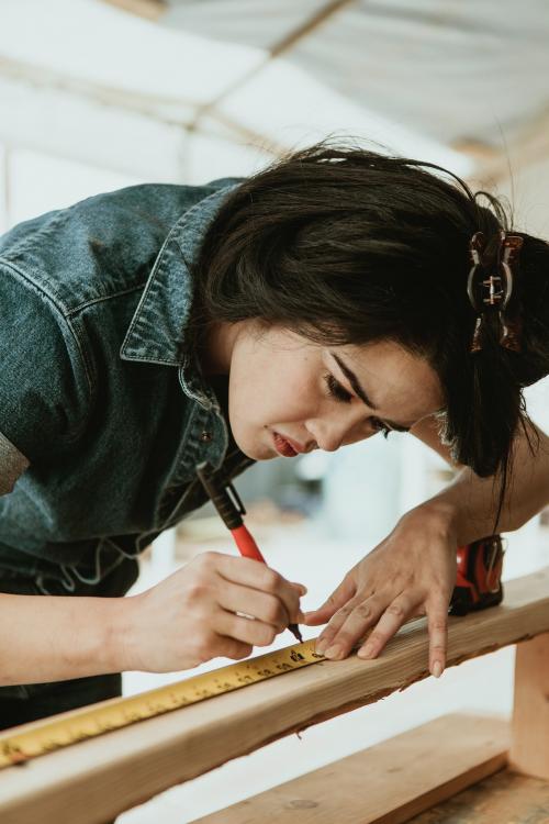 Female carpenter measuring the lumber - 1199246