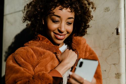 Cheerful black woman using her phone in downtown - 1200558