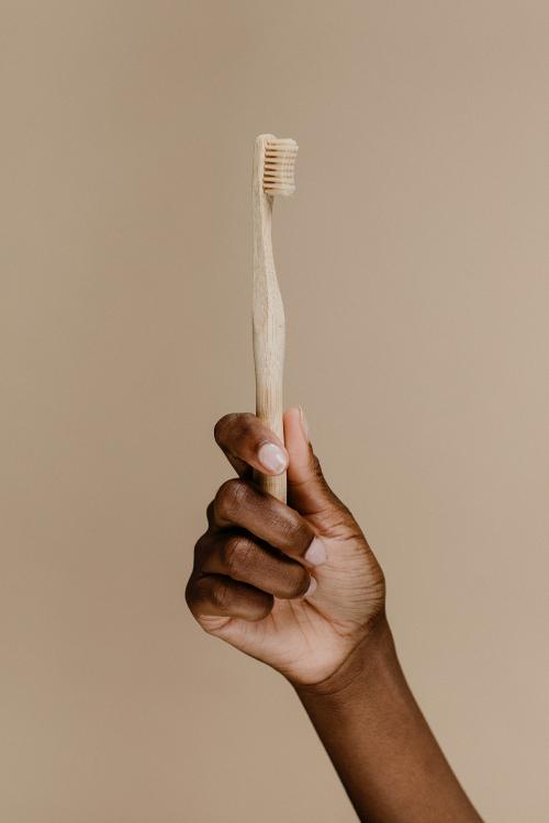 Black hand holding a wooden toothbrush - 1203372