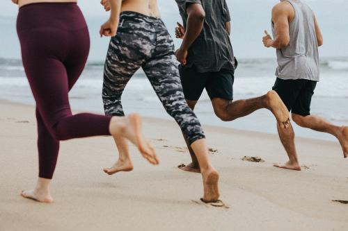 Friends running together at the beach - 1079805