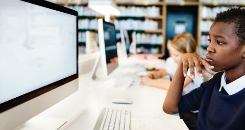 Elementary school student using a computer with an empty screen - 5459