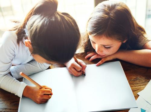 Girls writing and drawing on a white paper together copy space - 5461