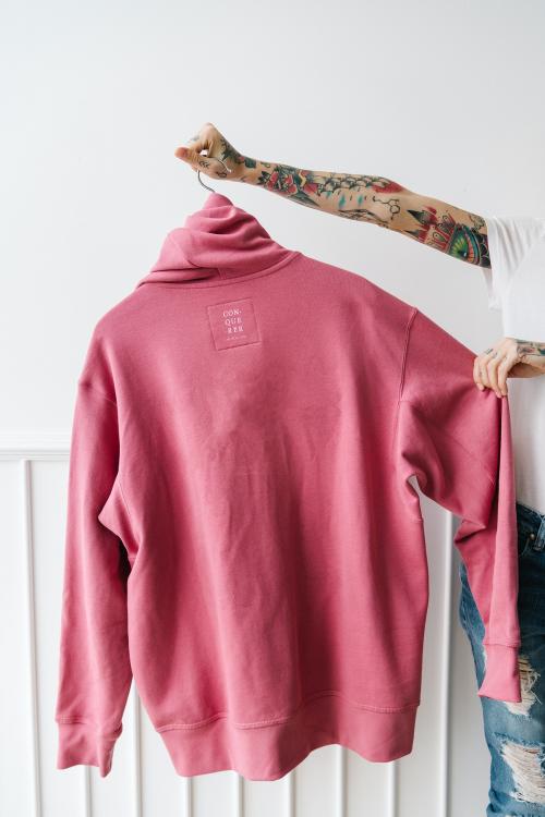 Tattooed woman holding a pink hoodie mockup - 1215344