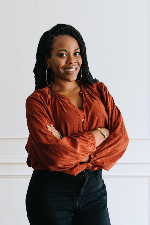 Happy empowering black woman standing by a white wall - 1220773