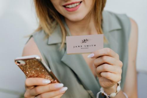 Friendly woman in sunglasses taking a photo of a business card with her smartphone - 1207990