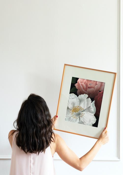 Curator hanging floral art frame mockup on the wall - 1209110