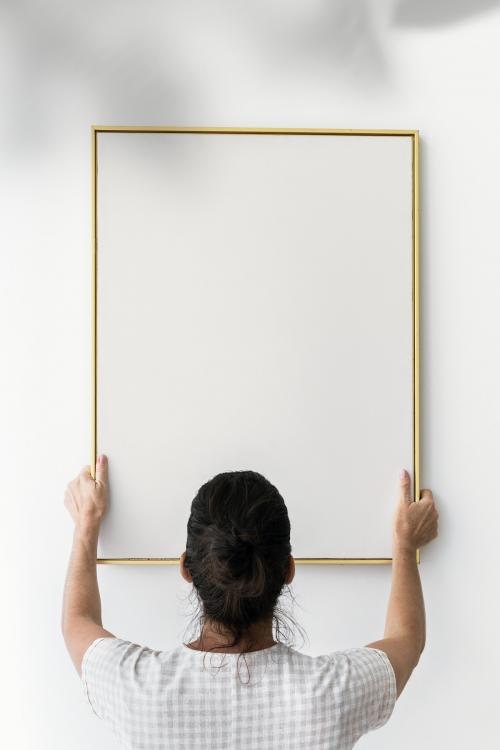 Curator putting up a golden frame mockup - 1210179