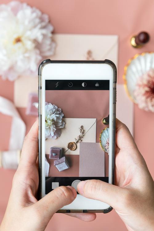 Woman taking a photo of a wedding ring and an invitation - 1212398