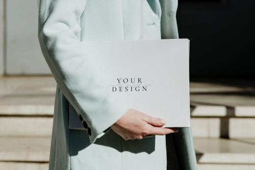 Woman in an overcoat carrying a white box in front of a building - 1198644