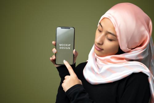 Muslim woman showing a mobile screen mockup in a green background - 2209646