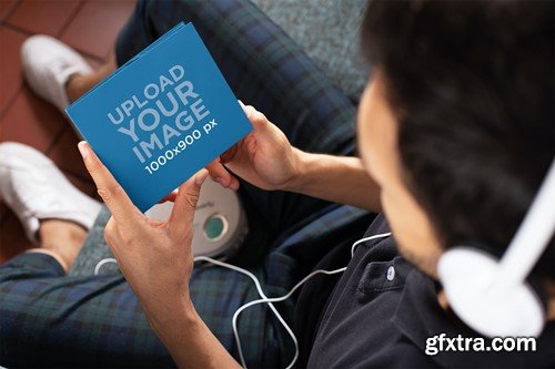 Mockup of a Man Holding a Digipak While Listening SAA8QJG