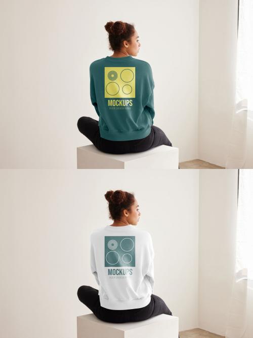 Mockup of woman wearing sweatshirt with customizable color sitting on plinth, rear view 640121285