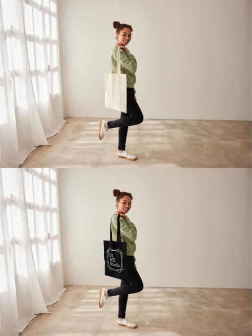 Mockup of woman standing holding customizable tote bag with one leg raised 640120713