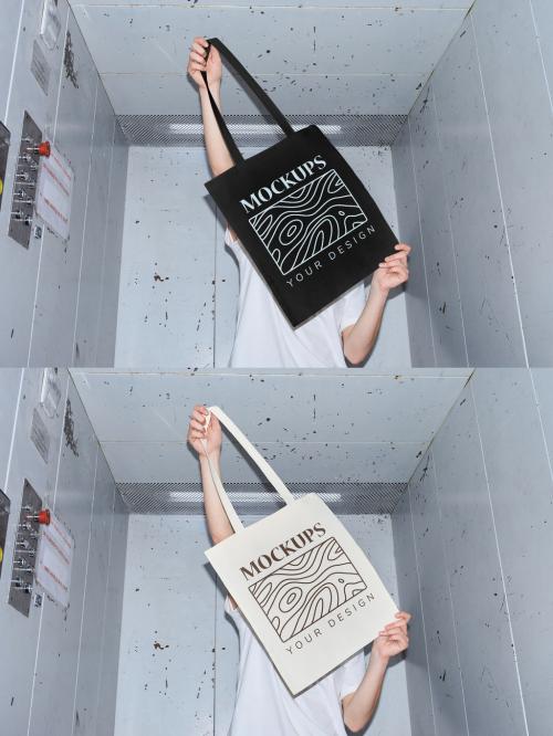 Mockup of woman holding customizable tote bag in front of face in elevator, camera flash 646703707