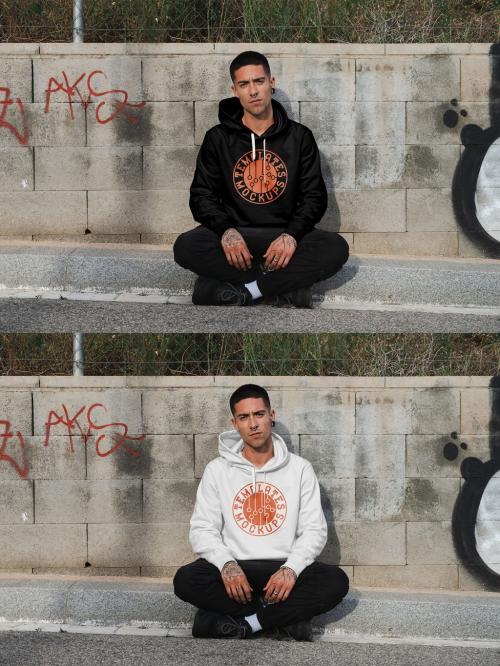 Mockup of man wearing hoodie with customizable color sitting on kerb with graffiti 644105215