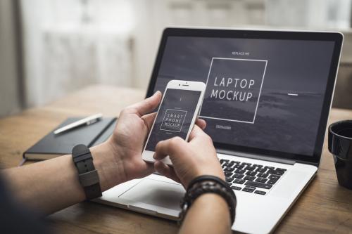 User with Smartphone and Laptop on Desk Mockup 2 - 141545448