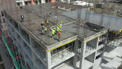 Premium stock video - An aerial tracking shot towards the right of a team of construction workers on a building