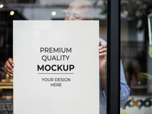 Person Putting Poster Mockup in Shop Window - 265500022