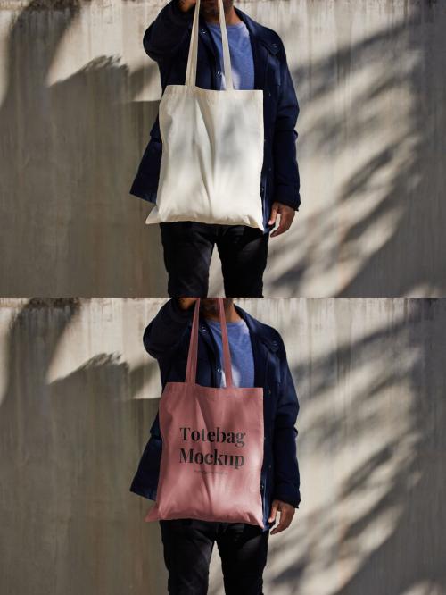 Man Holding Tote Bag Mockup on Concrete Wall
